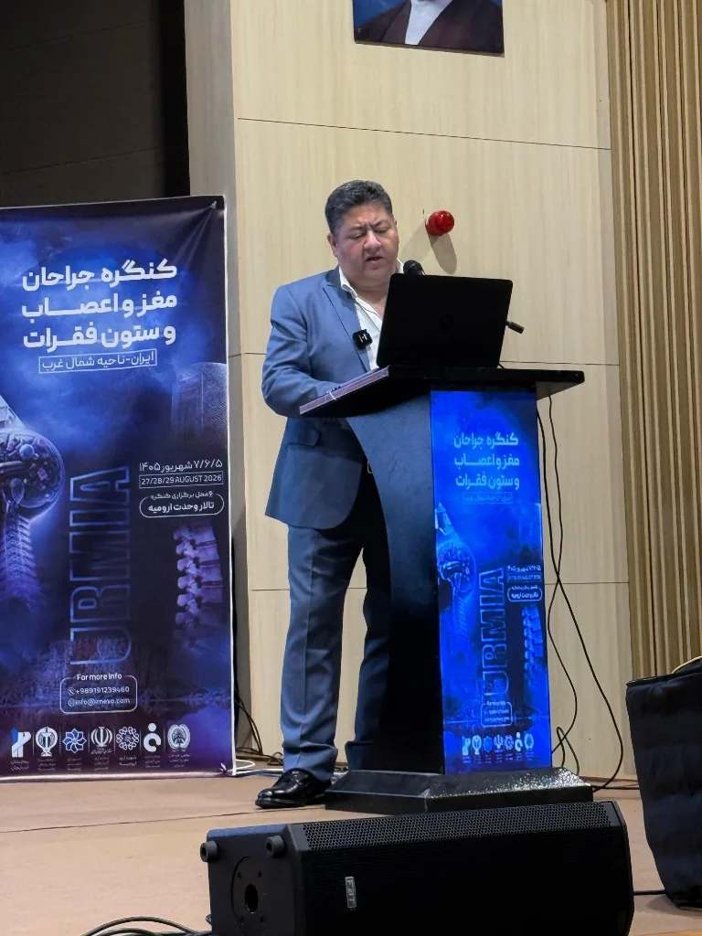 Prof. Guive Sharifi presenting at the podium in Vahdat Hall, Urmia